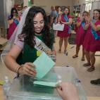 Una joven con velo y disfrazada para celebrar su despedida de soltera se dispone a introducir su papeleta de voto en una urna del IES La Caleta en el barrio de La Viña en Cádiz.