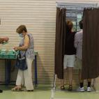 Varias personas cogen papeletas para ejercer su derecho al voto en el CEIP Malala de Mairena del Aljarafe en Sevilla, hoy domingo 19 de junio tras abrir los colegios electorales a las 09.00 horas para los duodécimos comicios autonómicos andaluces.