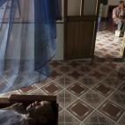 Lai Van Manh descansa en su cama, con su padre Lai Van Bien al fondo, recibiendo a unos vecinos, en Tuong An. El progenitor fue un agente de Inteligencia afectado por el agente, que ha tenido dos hijos con discapacidades varias.