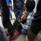 Una mujer yace desmayada mientras espera noticias de su hijo, aún sepultado bajo los escombros.