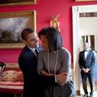 President Barack Obama hugs first lady Michelle Obama in the Red Room while Senior Advisor Valerie Jarrett (L) smiles prior to the National Newspaper Publishers Association (NNPA) at the White House on March 20, 2009, in Washington, D.C.