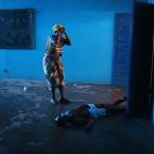 Omu Fereneh llora junto al cuerpo caído de su marido Ibrahim, que se desplomó inconsciente en un ala hospitalaria de ébola en Monrovia (Liberia) el 15 de agosto de 2014.