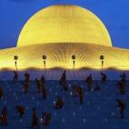 Monjes budistas encienden velas durante el día de Vesak, una celebración anual en recuerdo de Buda, en el templo Wat Dhammakaya en la provincia de Pathum Thani, a las afueras de Bangkok, Tailandia.