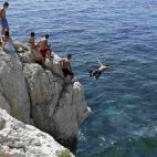 Un hombre salta desde una roca al Mar Mediterráneo durante el verano soleado en Marsella, Francia.