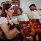 A waiter carries beer in one of the beer tents on the opening day of the 187th Oktoberfest beer festival in Munich, Germany, Saturday, Sept. 17, 2022. (AP Photo/Michael Probst)