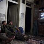 Combatientes de la oposición ven la televisión en un piso de la ciudad de Alepo (Siria)