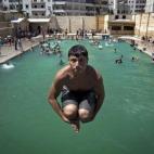 Un joven sirio de tira a una piscina en la ciudad siria de Alepo.