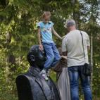 Una niña intenta bajar de la cabeza de la escultura de Lenin.