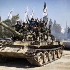 Miembros de las brigadas rebeldes celebrando hacen el símbolo de la victoria con los dedos sobre un tanque.