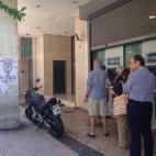 El mismo cartel, pegado junto a un cajero con la habitual cola.