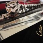 Pluma estilográfica de Cartier, edición limitada, modelo ST 190042. La pluma es de plata de ley y paladio tallado como con rayas atigradas; la tapa representa la figura de un tigre con ojos de aguamarina sobre un soporte de cristal triangular....