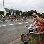 Poniendo las salchichas en la barbacoa mientras las vigilas con una mano y con la otra brindas por lo bonito que es el ciclismo y el gorro verde de tu amigo.
