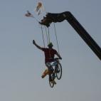 Subiéndote a una bici subida a su vez a una grúa mientras te la juegas haciendo una foto