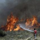Un voluntario trata de sofocar un incendio en el suburbio de Ilioupoli en Atenas (Grecia).