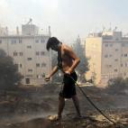 Un hombre intenta extinguir las llamas en el suburbio de Karea en Atenas (Grecia).