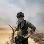 Un soldado intenta extinguir las llamas en el suburbio de Karea en Atenas (Grecia).