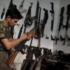 Abu Mohammad, de 39, chequea su AK-47 en su tienda de armas en Alepo (Siria)