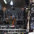 Abu Mohammad, 39, posa en su tienda de armas en la ciudad de Alepo, Siria.
