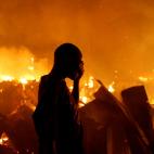 Un residente del barrio Kijiji de Nairobi no puede mirar c&oacute;mo las casas de sus alrededores se queman durante un incendio.