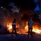 Dos manifestantes, delante de un fuego provocado