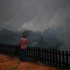 Un residente de Trespostos planta cara al incendio con una manguera.