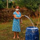 Una mujer se prepara contra el fuego llenando un cubo de agua antes de que el incendio alcance su aldea, cerca de Pedrogao Grande.