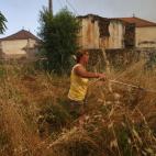 Una mujer trata de protegerse del fuego antes de que llegue a su zona con una manguera espray.