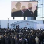 Asistentes a la ceremonia en el aeropuerto, con los reyes de B&eacute;lgica -Felipe y Matilde- en la pantalla.