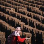 Una mujer pakistaní arregla ladrillos mientras trabaja en una fábrica en las orillas de Islamabad, Pakistán, el lunes 8 de marzo de 2010. (Muhammed Muheisen/AP)
