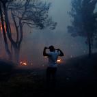 Un hombre se cubre la cara con una tela para protegerse del humo en Rafina.