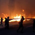 Un grupo de hombres carga con una manguera cerca de Rafina.