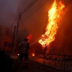 Un bombero trata de extinguir las llamas que queman un poste de Rafina.