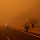 Un agente dirige el tr&aacute;fico para alejar del incendio a los conductores a las afueras de Kineta, cerca de Atenas.