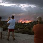 Un grupo de gente observa con impotencia pero a salvo c&oacute;mo se quema Rafina.