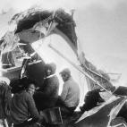 Tres de los supervivientes miran a c&aacute;mara desde la cola del avi&oacute;n accidentado.