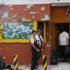 Varios empleados de Prosegur esperan en la destrozada entrada a sus oficinas durante la investigaci&oacute;n del suceso.