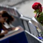 Una mujer firma el libro de condolencias colocado frente a la embajada francesa en Roma. En primer plano, una de tantas ofrendas atadas a la valla.