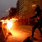 Un agente intenta apagar uno de los muchos incendios provocados en Per&uacute; durante las protestas por el golpe y destituci&oacute;n de Castillo