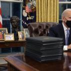 Biden, en su escritorio, con las fotos familiares de fondo.