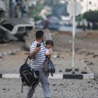 Un padre palestino y su hija abandonan su vecindario para dirigirse a un lugar más seguro mientras los aviones de combate israelíes continúan los ataques aéreos en la Franja de Gaza