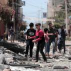 Un joven palestino camina sobre los escombros de la torre Al-Jawhara en la ciudad de Gaza, gravemente da&ntilde;ada, en la ciudad de Gaza