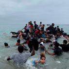 Un grupo de personas se hacen con una embarcación de las autoridades marroquíes en la playa de la localidad de Fnideq (Castillejos) para cruzar los espigones de Ceuta este martes en una avalancha de inmigrantes sin precedentes en España al re...