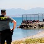 Un agente de la Guardia Civil observa a inmigrantes marroquíes llegados a nado este lunes a Ceuta.