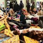 Refugiados ucranianos descansan, como pueden, en una estaci&oacute;n de tren en Polonia