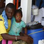 Un migrante subsahariano coge a su hija mientras esperan sentados sobre la cubierta del barco de rescate MV Phoenix en Vibo Valentia (Italia). Muchos refugiados tratan de cruzar a Italia vía Libia.