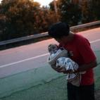 Un hombre espera con su bebé en otro campo de refugiados tras haber escapado de una evacuación forzosa en el campamento de Idomeni (Grecia).