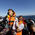 Una niña refugiada sonríe en brazos de su padre poco después de llegar en lancha a la isla griega de Lesbos tras cruzar una parte del mar Egeo desde Turquía el 18 de septiembre de 2015.