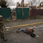 EDS NOTE: GRAPHIC CONTENT - A Ukrainian serviceman walks by lifeless bodies lying on a street in in the formerly Russian-occupied Kyiv suburb of Bucha, Ukraine, Saturday, April 2, 2022. As Russian forces pull back from Ukraine's capital region, ...