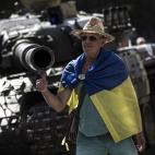 Un ciudadano ataviado con la bandera nacional posa ante un tanque capturado por las tropas ucranianas
