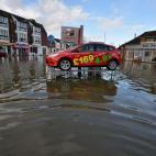 El agua casi alcanza a un coche sobre un expositor de un concesionario de Datchet. El Gobierno ha declarado 14 alertas graves y otras 350 menos severas.